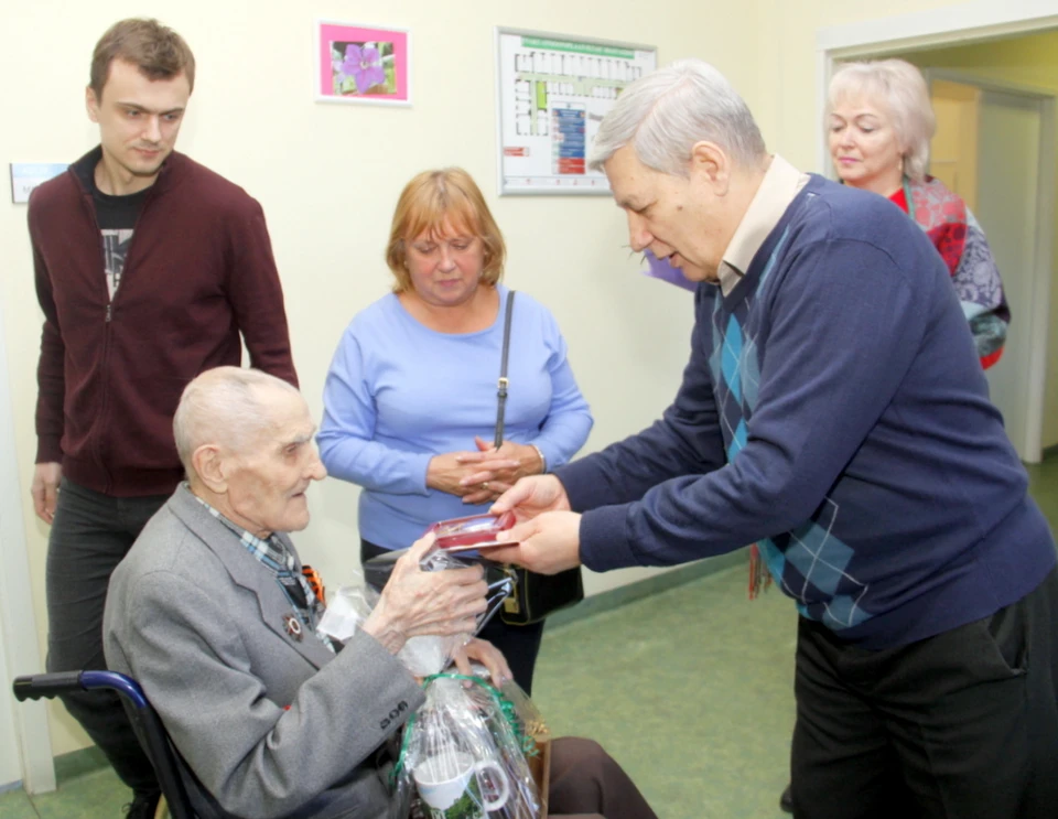 Валерий Тумко вручает юбиляру медаль, посвященную 100-летию Вооруженных Сил СССР.