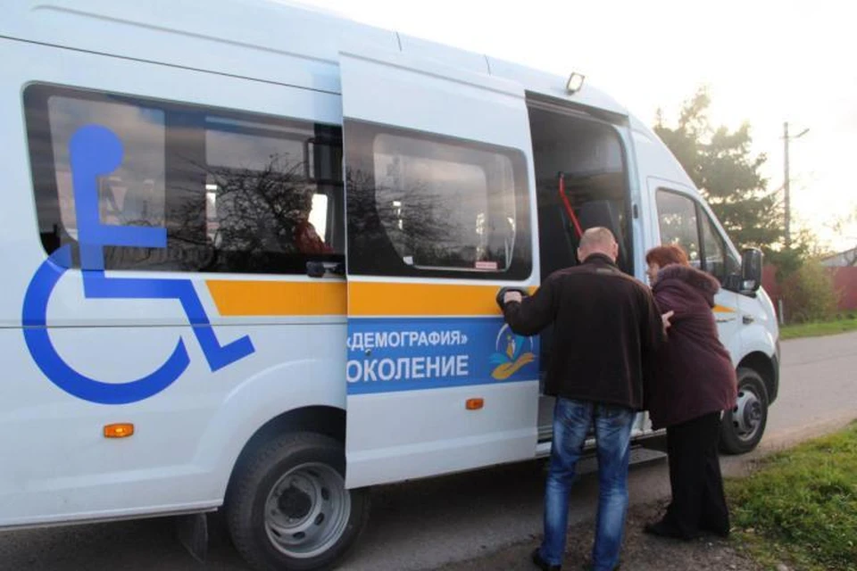 Водитель Вадим Апшлат помогает пассажирам сесть в микроавтобус.