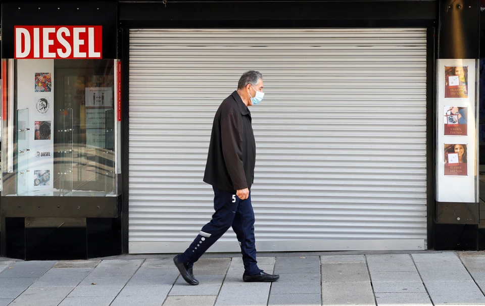Житель Вены проходит мимо закрывшегося из-за мер карантина магазина.