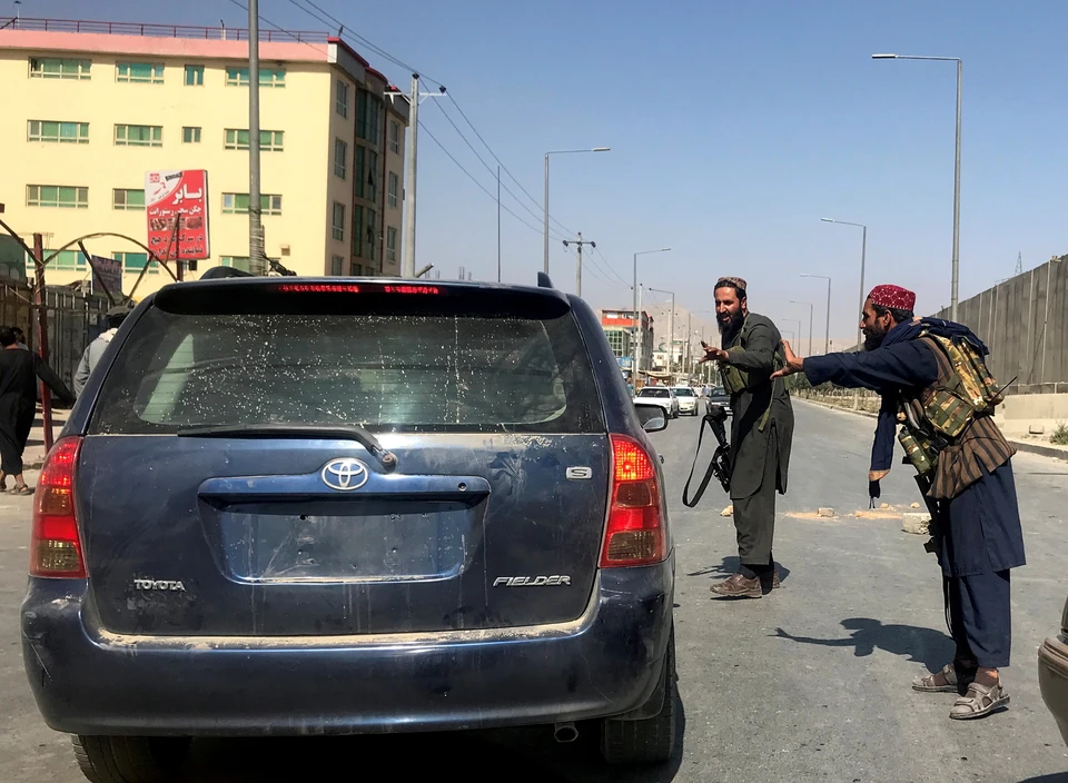 Бойцы "Талибана"* пытаются остановить автомобиль на подступах к аэропорту Кабула.