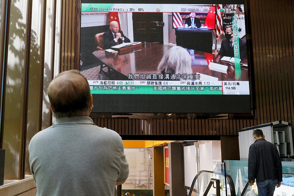Гонконг. Прохожий смотрит выпуск новостей о переговорах Си Цзиньпина и Байдена.