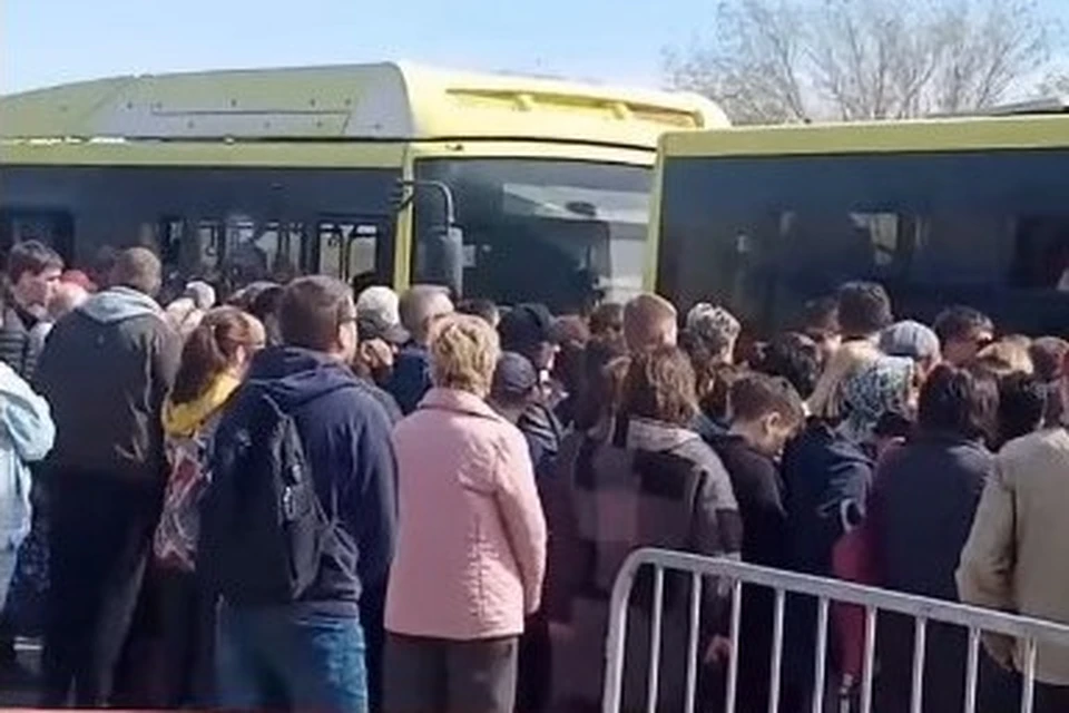 Сотни людей ждут своей очереди, чтобы попасть в автобус и доехать до кладбища. Фото: стоп-кадр с видео