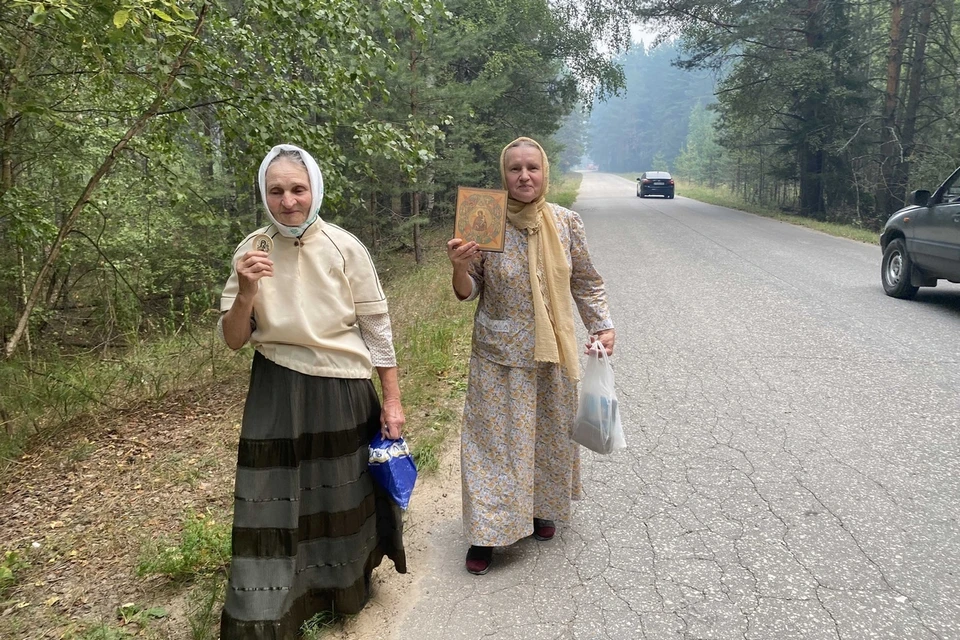 Пока профессиональные формирования борются с пожаром, две жительницы деревни Картоносово молятся в местном храме, а затем проходят Крестным ходом с иконами.