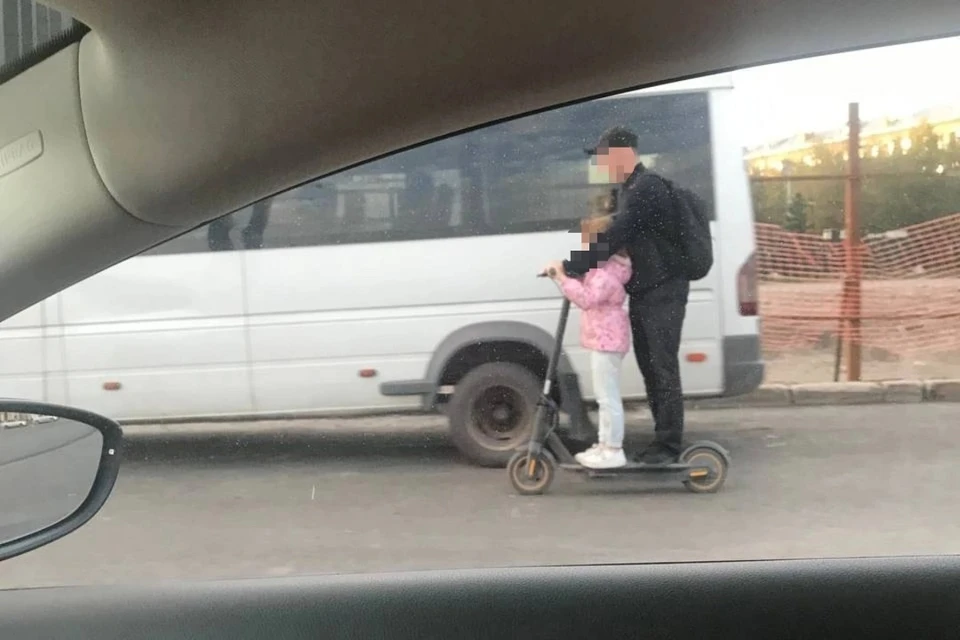 На оживленной автодороге в Новосибирске заметили мужчину и девочку на самокате. Фото: АСТ-54.