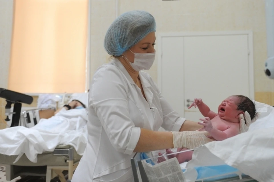 Медицинский работник осматривает новорожденного ребенка.