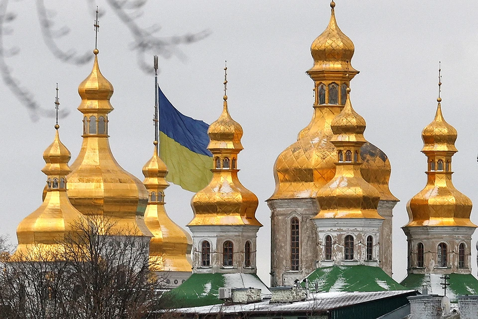 Купола Успенского собора Киево-Печерской лавры на фоне флага Украины в Киеве.