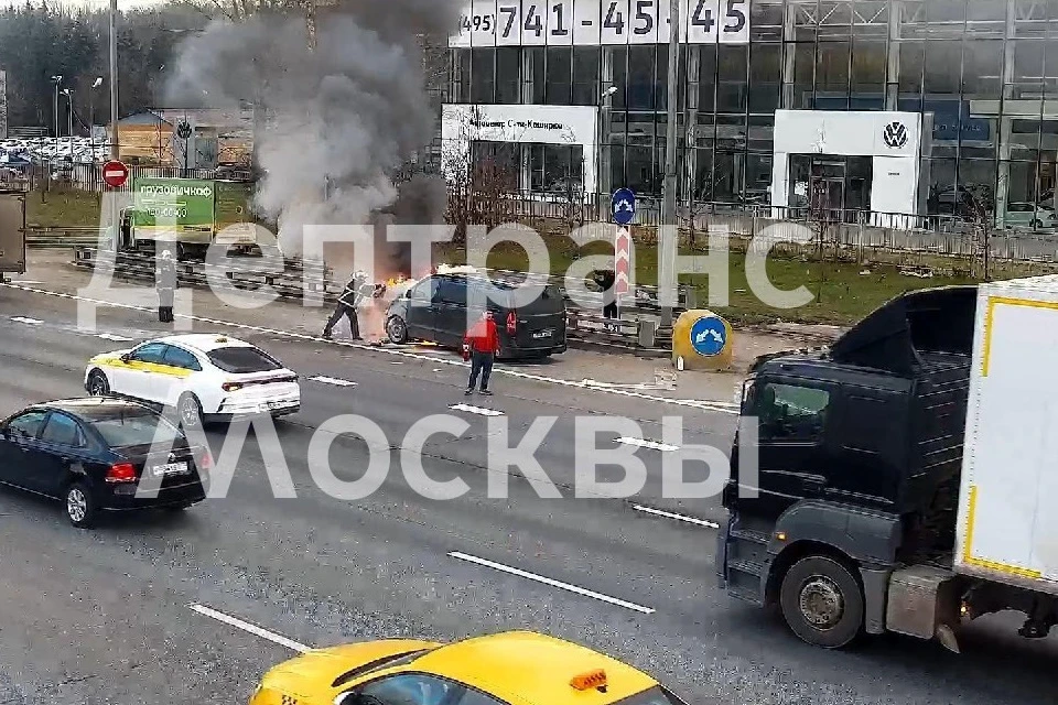 От автомобиля валит густой черный дым, видно языки пламени