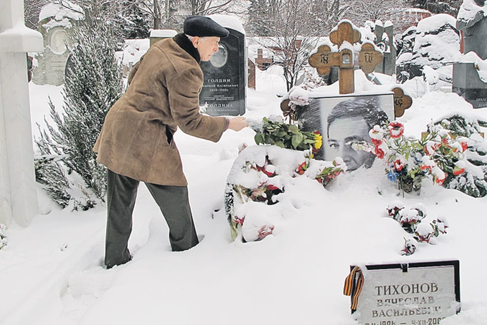 Народный артист СССР Василий Лановой сметает снег с фотографии на могиле своего друга Славы Тихонова.