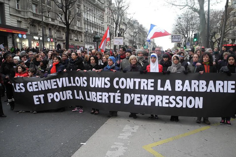 Участники демонстрации держат плакат: "Мы против варварства и за свободу выражения"