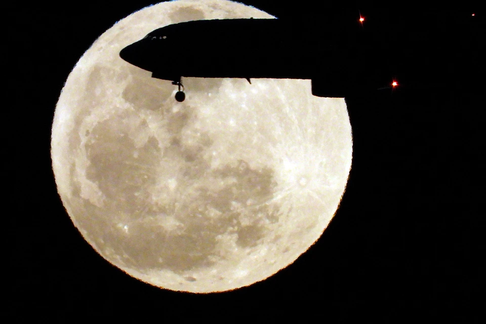 Самолет заходит на посадку на острове Град-Канария на фоне полной Луны. Фото: REUTERS